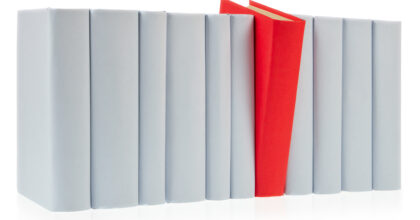 Red book falls out of row of grey books