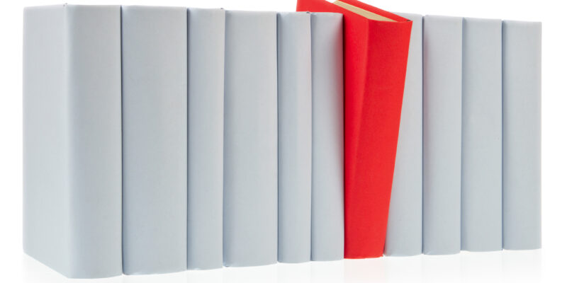 Red book falls out of row of grey books