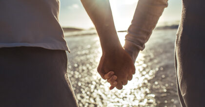 Cropped shot of an older couple holding hands at the beach